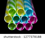 Small photo of Colourly striped plastic drinking straws, black underground background