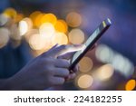 Female using her mobile phone, city skyline night light  background