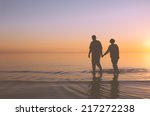 Senior couple walking holding hands at sunset