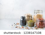 Healthy food, dieting, nutrition concept, vegan protein source. Assortment of colorful legumes in jars, lentils, soy kidney beans, chickpeas on a modern kitchen table. Copy space background