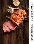Small photo of Sliced smoked gammon on a wooden table with addition of fresh herbs and aromatic spices, top view. Natural product from organic farm, produced by traditional methods