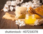 Honey dripping from a wooden honey dipper in a jar on wooden grey rustic background. Propolis and bee honey. Spring natural product concept.