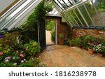 Small photo of TICEHURST, EAST SUSSEX, ENGLAND - MAY 18, 2019: Old Greenhouse interior with plants and flowers.