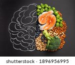 Chalk hand drawn brain with assorted food, food for brain health and good memory: fresh salmon fish, green vegetables, nuts, berries on black background. Foods to boost brain power, top view