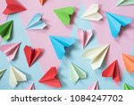 colorful paper airplanes on pastel pink and blue colored background. childhood,freedom and diversity concept