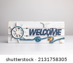 Small photo of Welcome Sign Made from Wood in a Seaside Decor with Ships Helm and Seagull Flying. Blue Lettering 'Welcome' with Rope and shells. Product against white background.