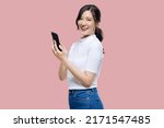 Attractive Young Asian woman pointing finger to mobile smartphone on isolated pink background.