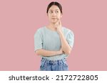 Beautiful young Asian girl thinking and looking upwards. The concept of content thinks about future isolated on pink background.