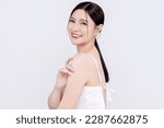 Close up beautiful young Asian woman with clean fresh skin touching shoulder gently on white background. Cosmetology, body skin care beauty and spa.