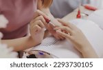 Small photo of Close up Asian nail stylist apply color for a perfect polish nail to customer. Manicure concept. Nail salon services.