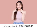 Beautiful young Asian woman pointing finger to her teeth on isolated pink background. Facial and skin care concept for commercial advertising.