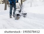 Snow blower in action clearing a residential driveway after snow storm