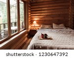 Rustic interior of log cabin bedroom. Cozy bed by big window. Breakfast on a tray in hotel.