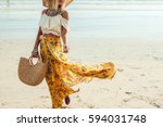 Girl wearing floral maxi skirt walking barefoot on the sea shore, Thailand, Phuket. Bohemian clothing style.