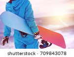 Woman holding snowboard in hands. Closeup view. Snowboarder or snowboarding concept at sunrise or sunset time