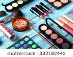 Makeup brush and cosmetics on blue wooden table