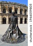 Small photo of Nimes, France - March 31, 2019: statue of toreador in front of Nimes Roman amphitheater