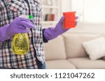 Small photo of Unrecognizable woman with cleaning equipment ready to clean house. Cropped girl holding rag and spray detergent, professional cleaning service concept, copy space