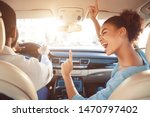 Happy afro couple driving in car and girl singing song, enjoy tavel by auto