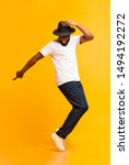 Small photo of Cheerful african man dancing on tiptoes, copy michael jackson style on yellow studio background