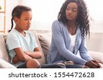 Small photo of Disobedient child. Disappointed black mother looking at her little daughter with reproach, sitting on couch at home