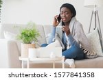 Sick african american girl sitting on couch, holding thermometer and calling family doctor for counseling, free space