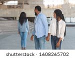 Infidelity concept. Black millennial guy distracted to another woman while walking with his girlfriend in city, selective focus