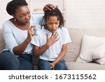 Small photo of Preventing Attack. Black woman giving blue asthma inhaler to her sick breathless child at home, free space