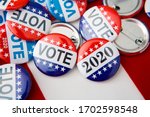Red, white, and blue vote buttons on background with American flag, elections 2020