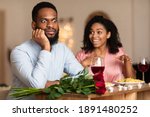 Small photo of Bad Date. African American Couple Having Unsuccessful Blind Date In Restaurant, Funny Disappointed Shoked Black Man Feeling Embarrassment Listening To Excited Woman Talking