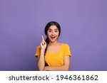 Small photo of Inspiration, Creativity, Solution, Eureka concept. Portrait of excited young indian woman in yellow t-shirt raising finger up and smiling, having wow creative idea, purple studio background, copyspace