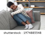 Small photo of Depression Concept. Portrait Of Sad African American Female Sitting On Sofa At Home, Upset Black Lady Suffering Melancholy, Having Bad Mood Or Nervous Breakdown, Feeling Bad And Lonely, Closeup