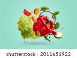 Small photo of Various ripe vegetables levitating in the air over blue background. Fresh bell-pepper, lettuce, carrot, tomatoe, basil leaves, cucumber, onion, peas floating up, healthy recipes for summer concept