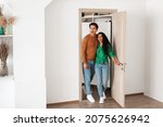 Small photo of Wow. Portrait of excited emotional couple walking in their apartment, entering new home, happy young guy and lady standing in doorway of modern flat, looking at design interior together, coming inside