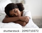 Small photo of Loneliness, depression, emotional burnout concept. Closeup of depressed young black lady sitting alone on floor next to bed at home, leaning on her hands, staring at copy space, heave thoughts