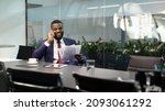 Small photo of Wealthy black guy in suit entrepreneur having phone conversation with his assistant or business partner, sitting at table with digital tablet on, looking at documents, panorama with copy space