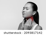 Small photo of Black and white photo of young asian woman suffering from tonsillitis, pulping her lightened in red neck, experiensing acute throat pain, monochrome panorama with copy space, closeup