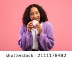 Small photo of Beautiful young African American lady eating chocolate bar, enjoying yummy dessert over pink studio background. Unhealthy nutrition, cheat meal, forget about diet concept