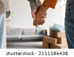 Small photo of Closeup of young couple holding hands and new house key, moving in together. Unrecognizable boyfriend and girlfriend relocating to their own property, cropped view. Mortgage, real estate concept