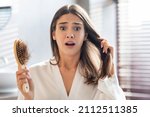 Small photo of Shocked Young Woman Worried About Hairloss After Brushing Hair In Bathroom, Upset Female Holding Comb Full Of Fallen Hair And Looking At Camera With Despair, Emotionally Reacting To Health Problems