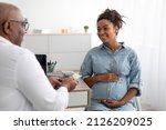 Pregnancy, Obstetrics, Gynaecology, Medicine, Healthcare And People Concept. Black male gynecologist giving pills to smiling pregnant woman during appointment at hospital. Visit To A Doctor Concept