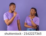 Small photo of Don't Tell Anyone. Emotional Black Guy And Lady Holding Finger On Lips, Showing Silent Gesture Making Mute Hush Sign Posing Standing Isolated On Purple Violet Studio Wall, Looking At Each Other