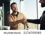 Small photo of Business partnership. Smiling male entrepreneurs shaking hands, celebrating cooperation agreement at office. Two happy businessmen handshaking after successful deal at modern company