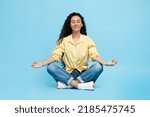Small photo of Mindfulness. Calm Arabic Woman Meditating Sitting In Lotus Position Doing Om Gesture Relaxing Over Blue Studio Background. Yoga Exercise And Meditation Concept