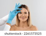 Happy pretty blonde middle aged woman gets cosmetic injection in her forehead. Hyaluronic acid injection for facial rejuvenation procedure. Women in beauty salon. Plastic surgery clinic.