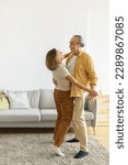 Small photo of Loving senior spouses looking at each other with tenderness while dancing together in living room at home, vertical shot. Two pensioners enjoying happy life moments on retirement