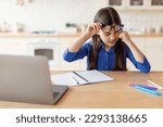 Small photo of Eyestrain Problem. Tired Schoolgirl Rubbing Sore Eye Doing Homework On Laptop, Suffering From Fatigue And Dry Eyes Syndrome, Wearing Glasses Sitting At Desk At Home. Children Eyesight Issues