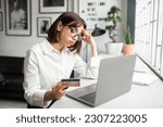 Small photo of Cheated and disappointed young businesswoman working in cozy office or cafe, holding bank credit card and trying to make purchase, online fraud and deception