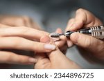Small photo of Nails Polish Procedure. Closeup Of Female Hands While Manicurist Filing and Polishing Fingernails With Professional Device, Making Hardware Manicure Using Electric Machine In Beauty Studio, Cropped
