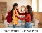 Back to School. Happy middle eastern mom preparing preteen schoolgirl daughter with backpack for first school day at home, looking at kid and encouraging her to enjoy classes in the morning